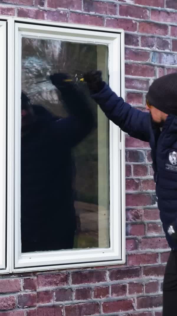 Clear Guard field test showing an exterior security-film installation being struck while the filmed glass remains in the frame
